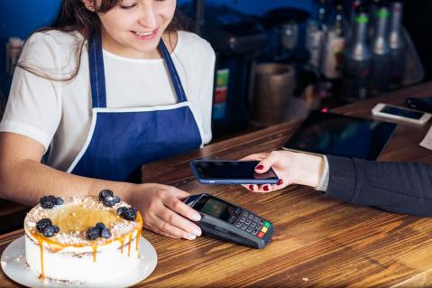 Frau bezahlt mit ihrem Smartphone in Café
