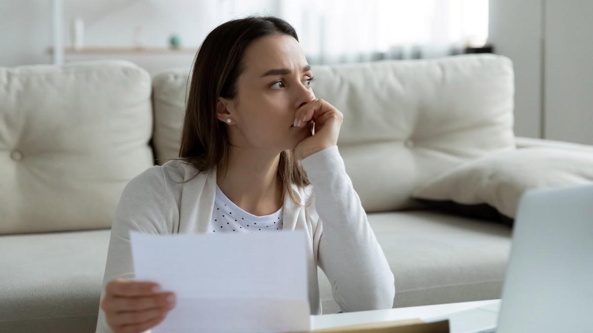 Junge Frau mit Brief in der Hand schaut nachdenklich